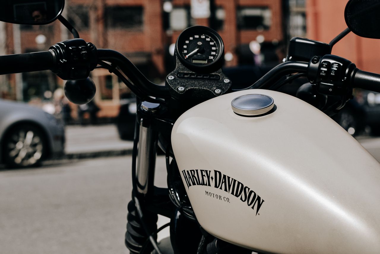 Retro styled white motorcycle with black handlebar parked on sunny street in city
