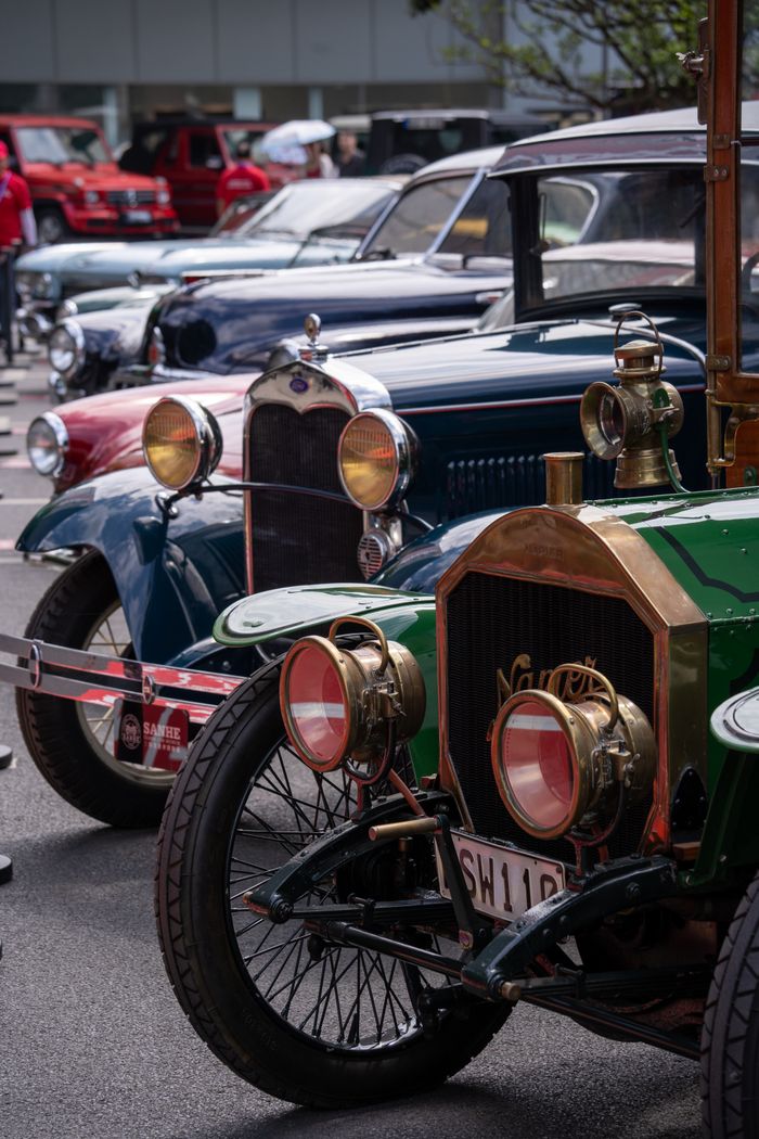 Row of classic vintage cars at an outdoor auto show, showcasing elegant antique designs.