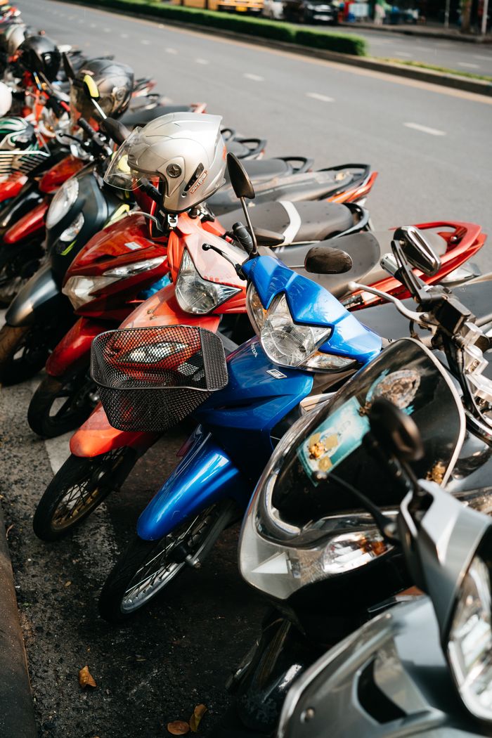 A row of colorful motor scooters parked along a city street, depicting urban transportation.